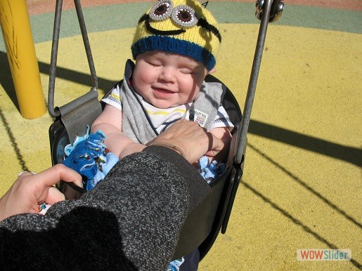 a smiling baby is enjoying the swingset